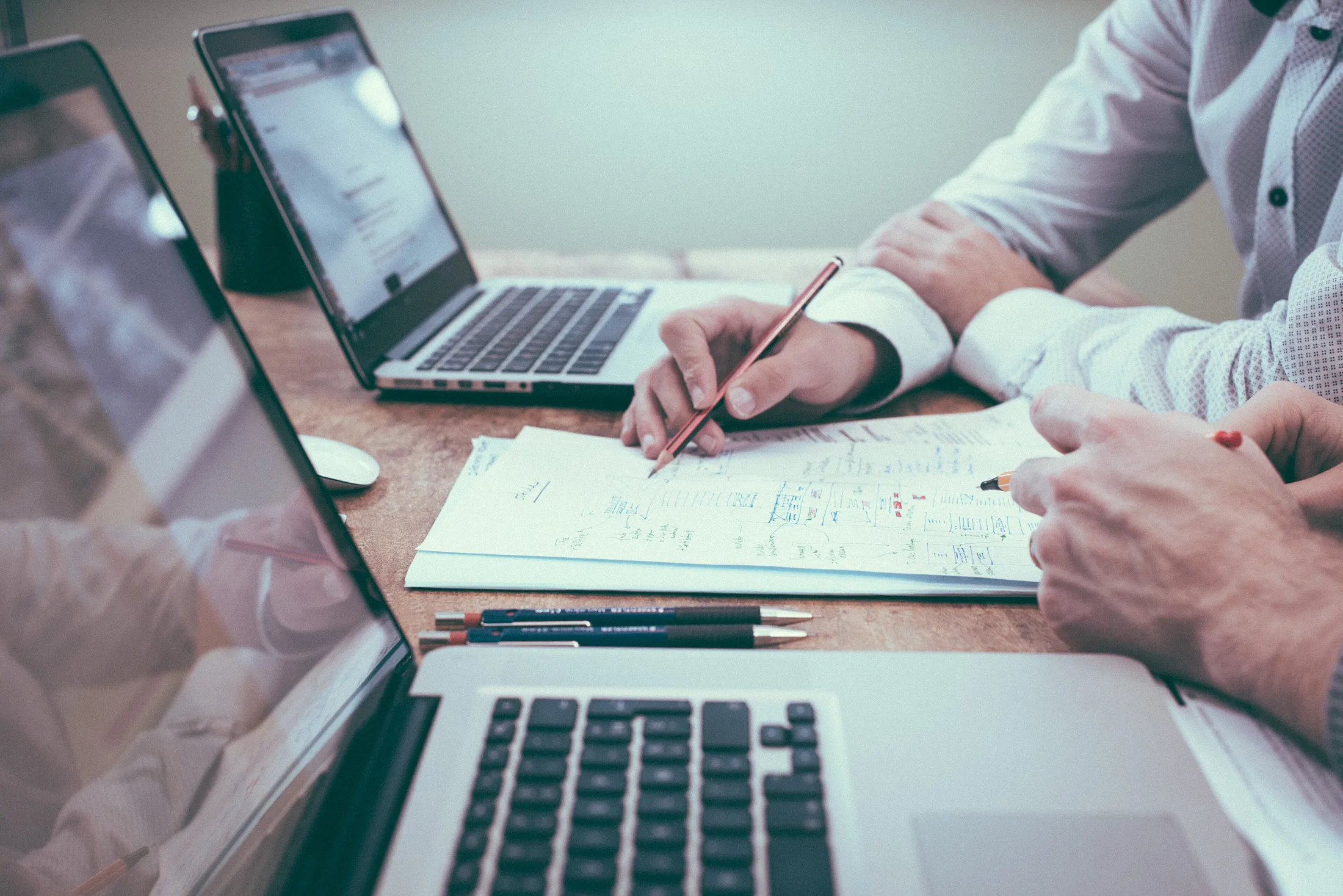 Dos personas planificando sobre un cuaderno, con portatiles en la mesa
