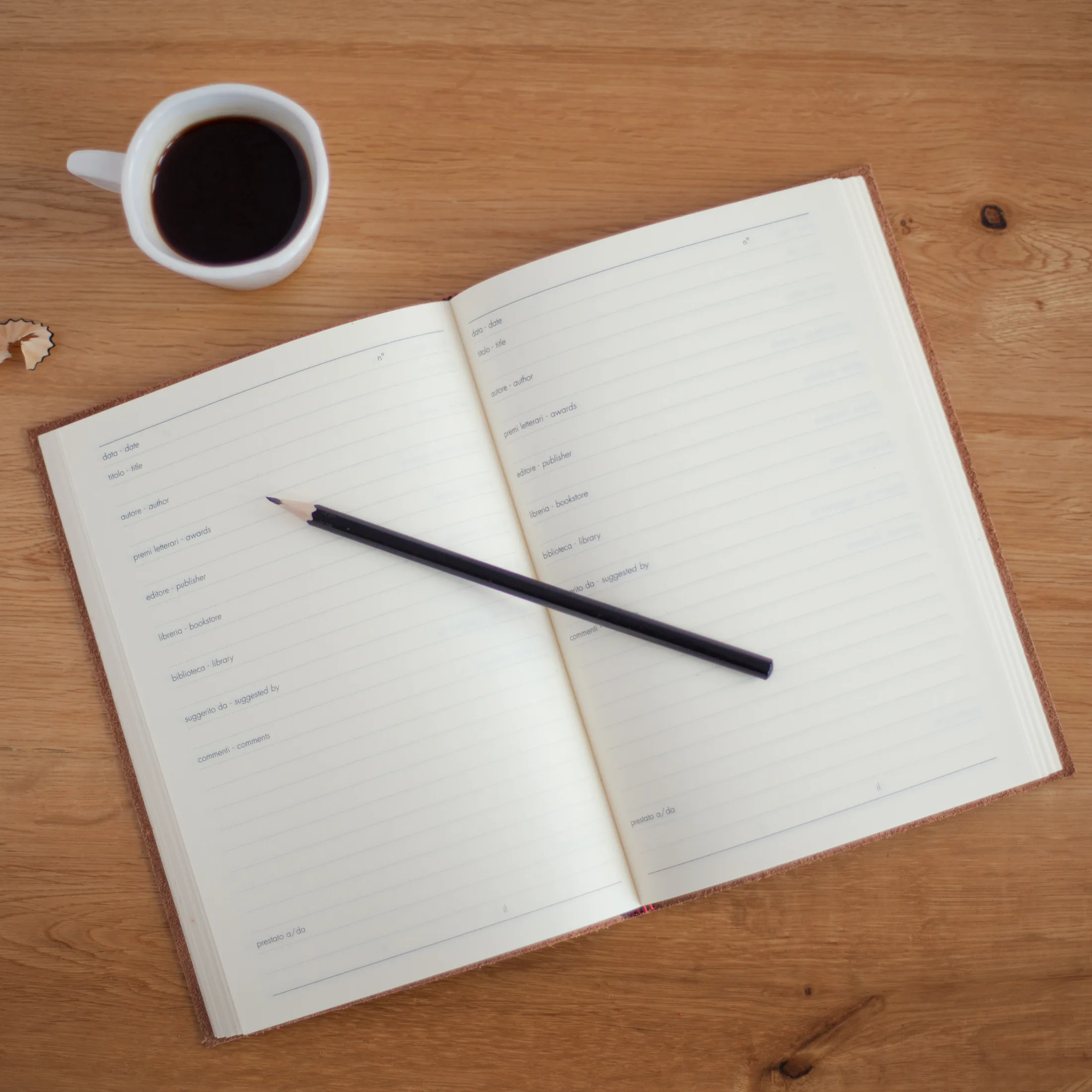 Cuaderno abierto con un lapiz y una taza de cafe